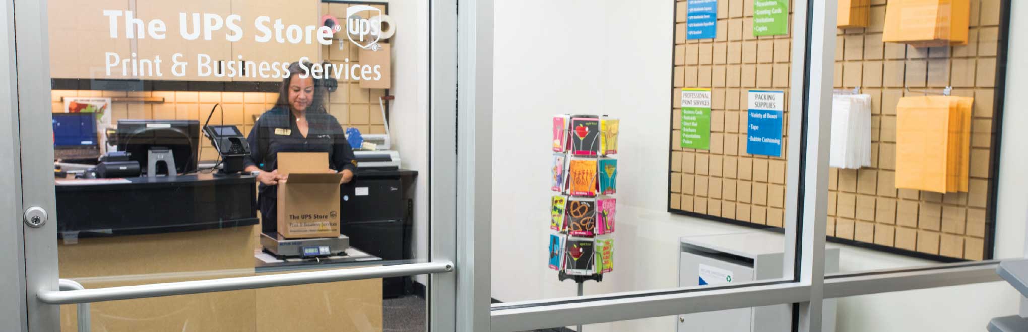 A woman weighing a box inside a The UPS Store
