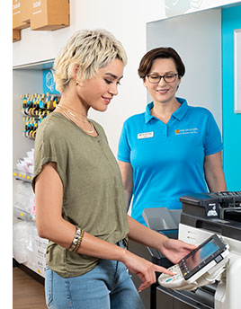 A The UPS Store employee helping a female at the printer